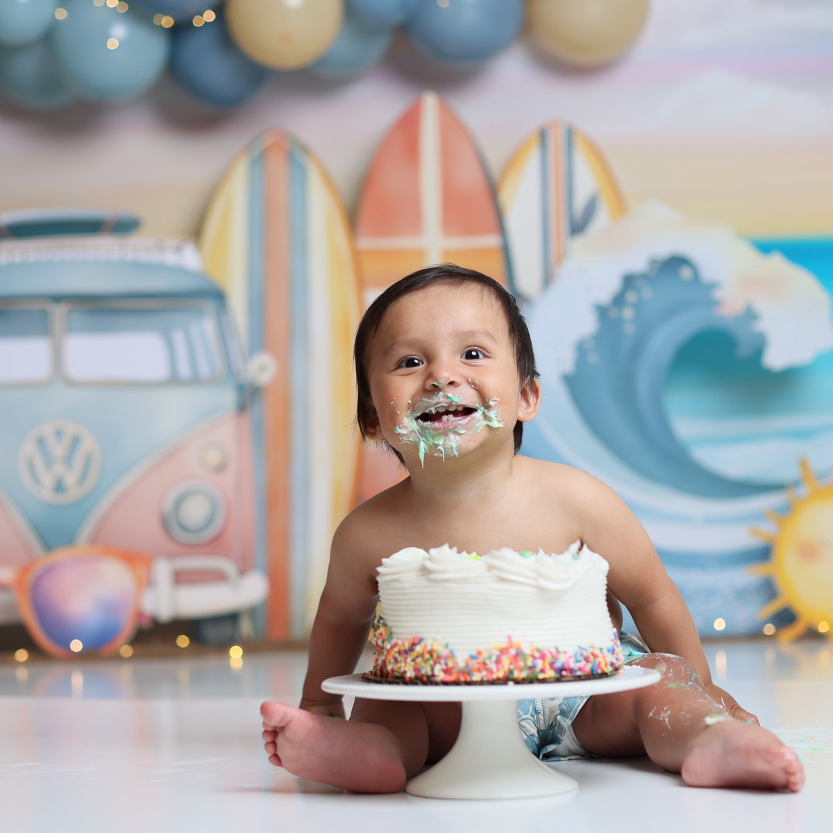 A baby enjoying cake in a teal, cream and champagne surf-themed set