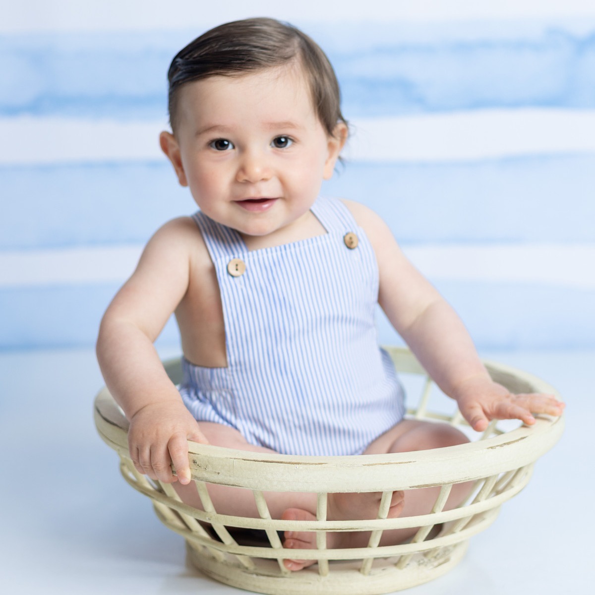 A smiling baby sitting in a blue and white studio set