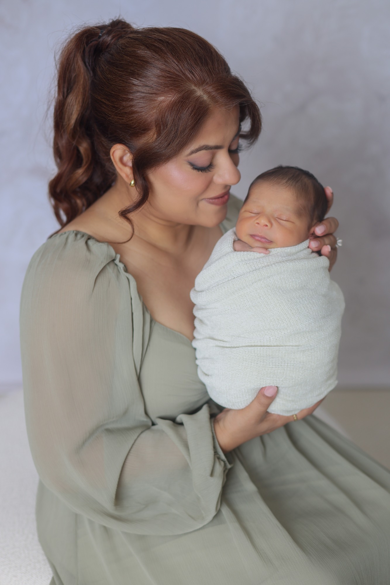 A mother holding her sleeping newborn close to her face