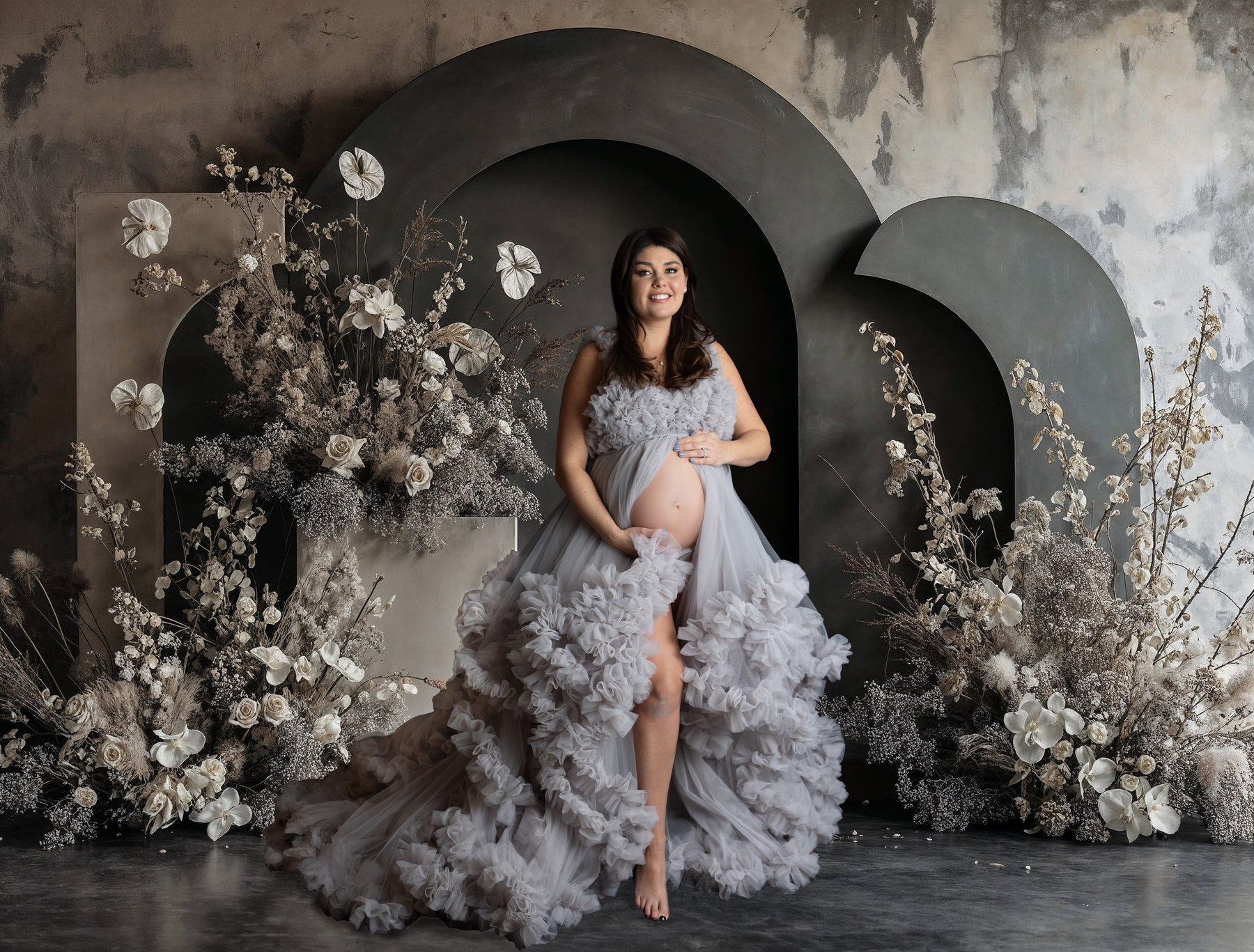Maternity portrait in a lavender gown surrounded by a dramatic dark floral installation