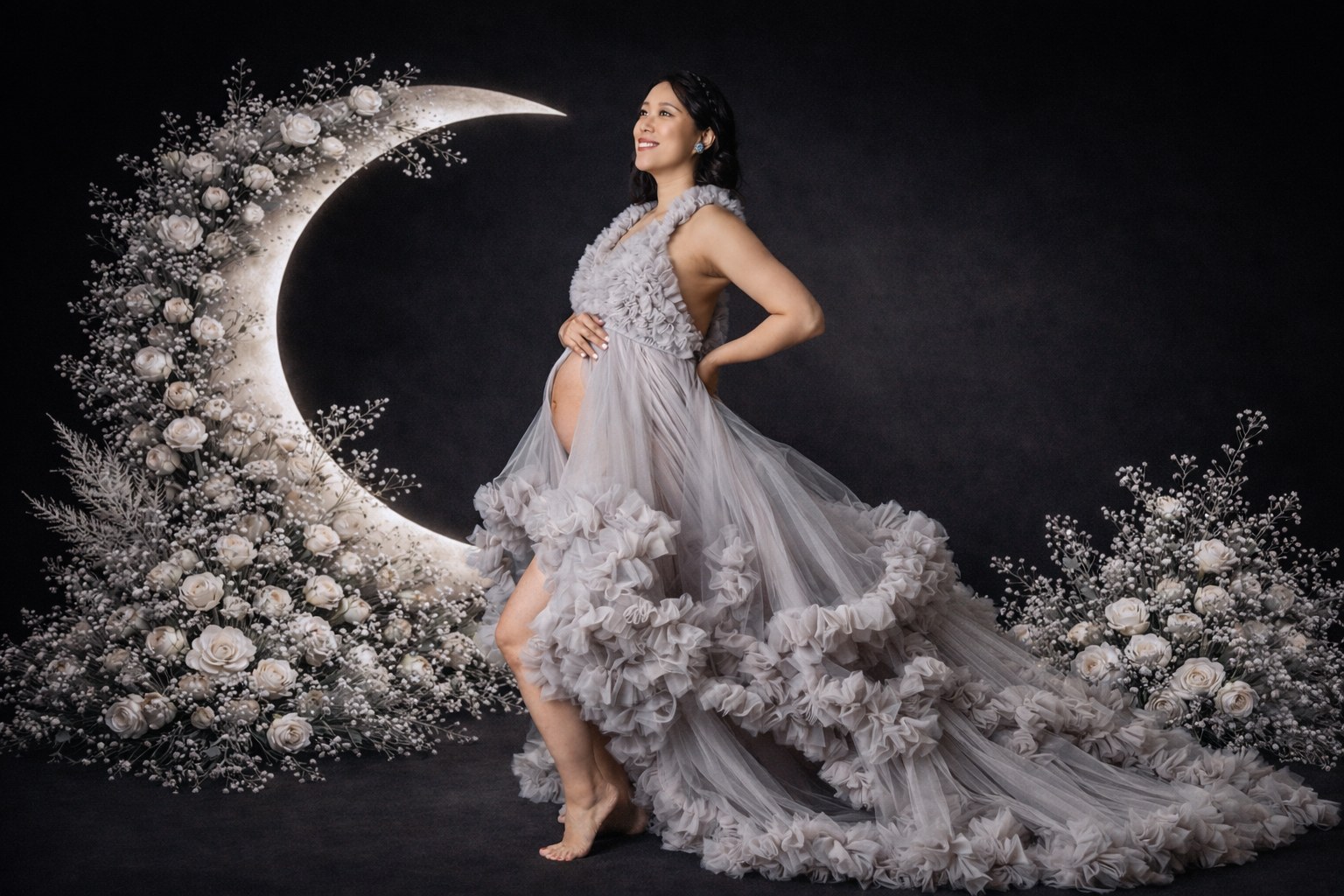 Maternity portrait in a lavender ruffled gown beside a floral crescent moon