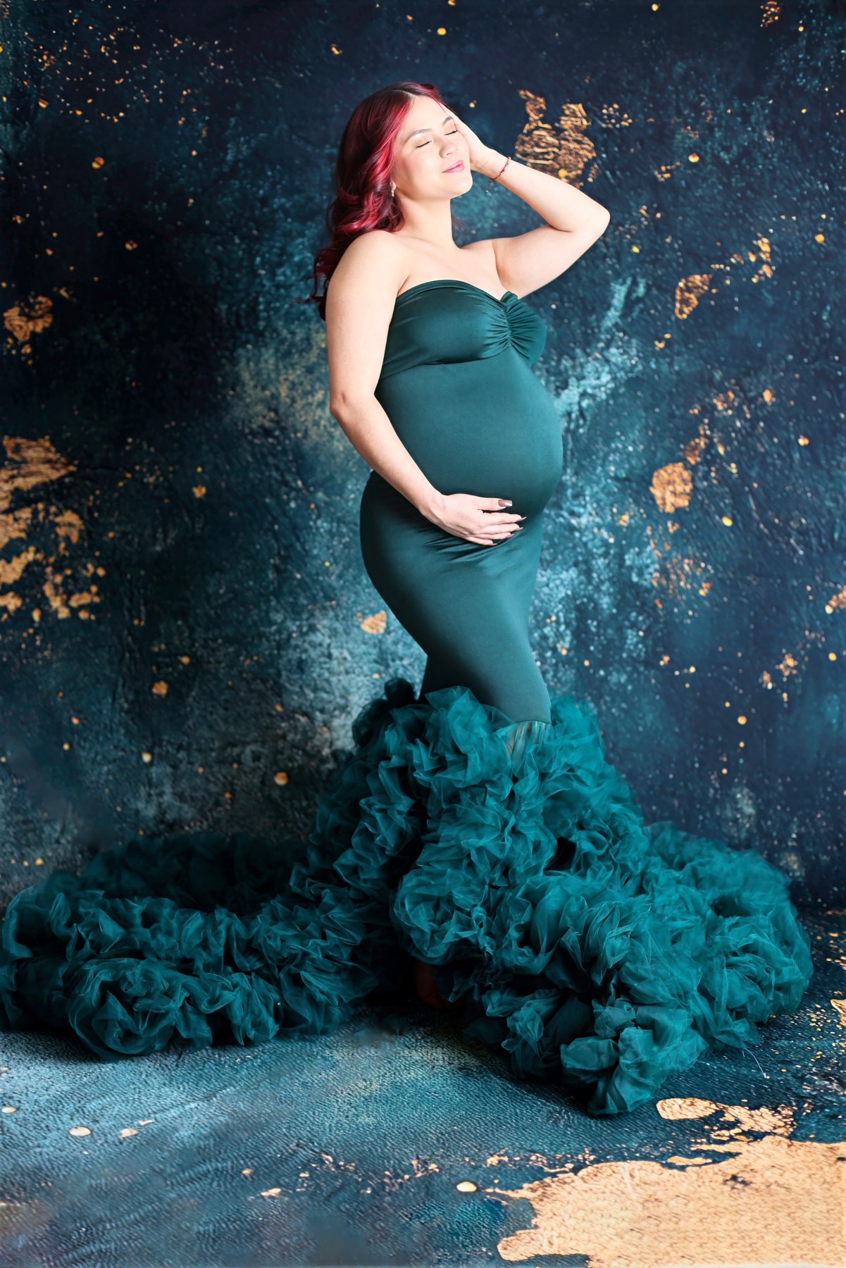 Maternity portrait in a teal mermaid gown against blue and gold