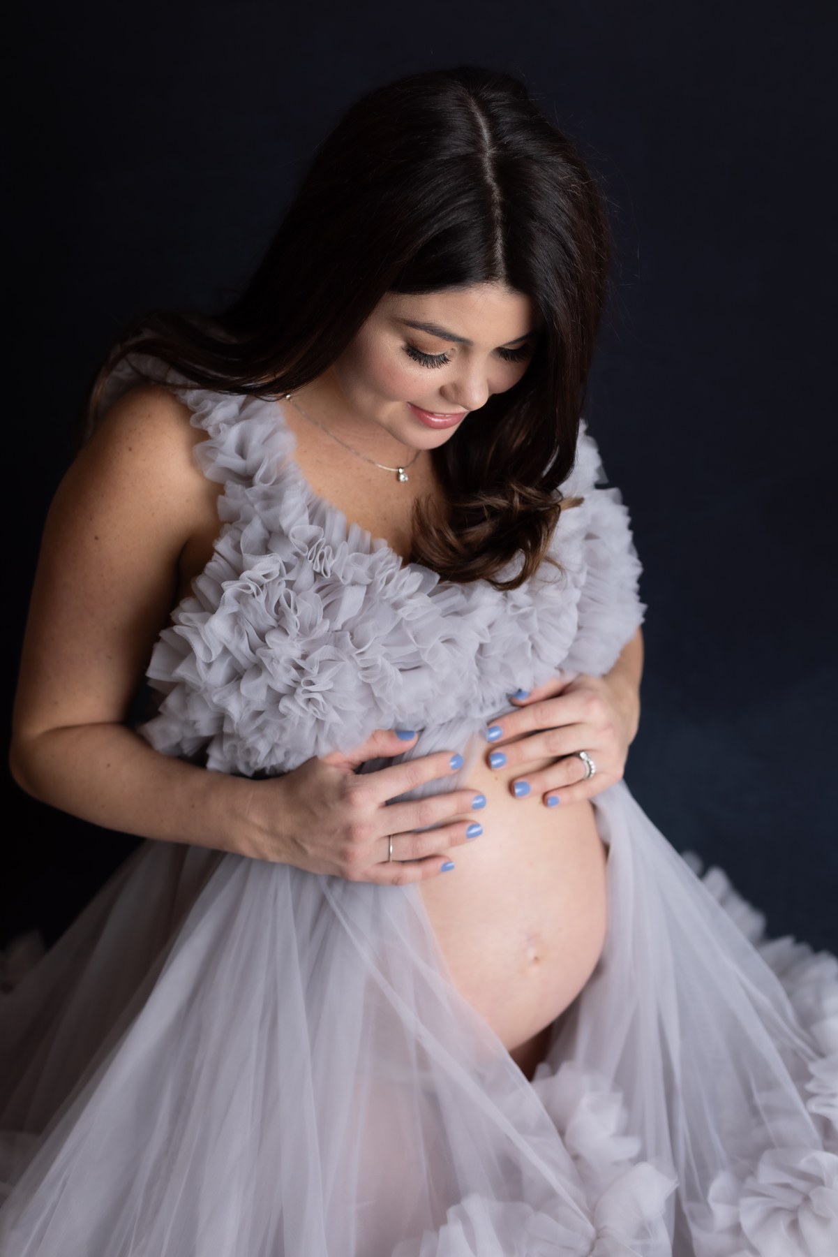 An expectant mother looking toward her bump in a lavender gown