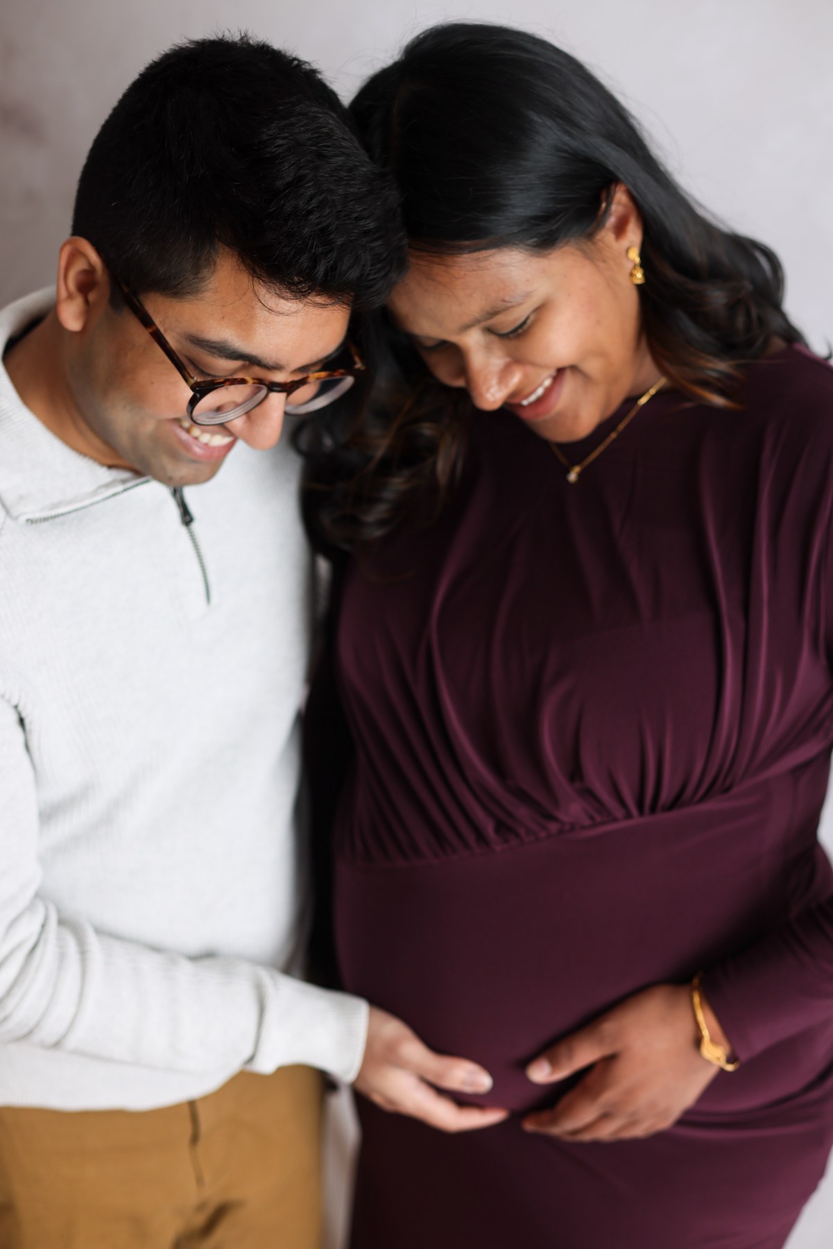 Expectant parents smiling together with hands on the bump