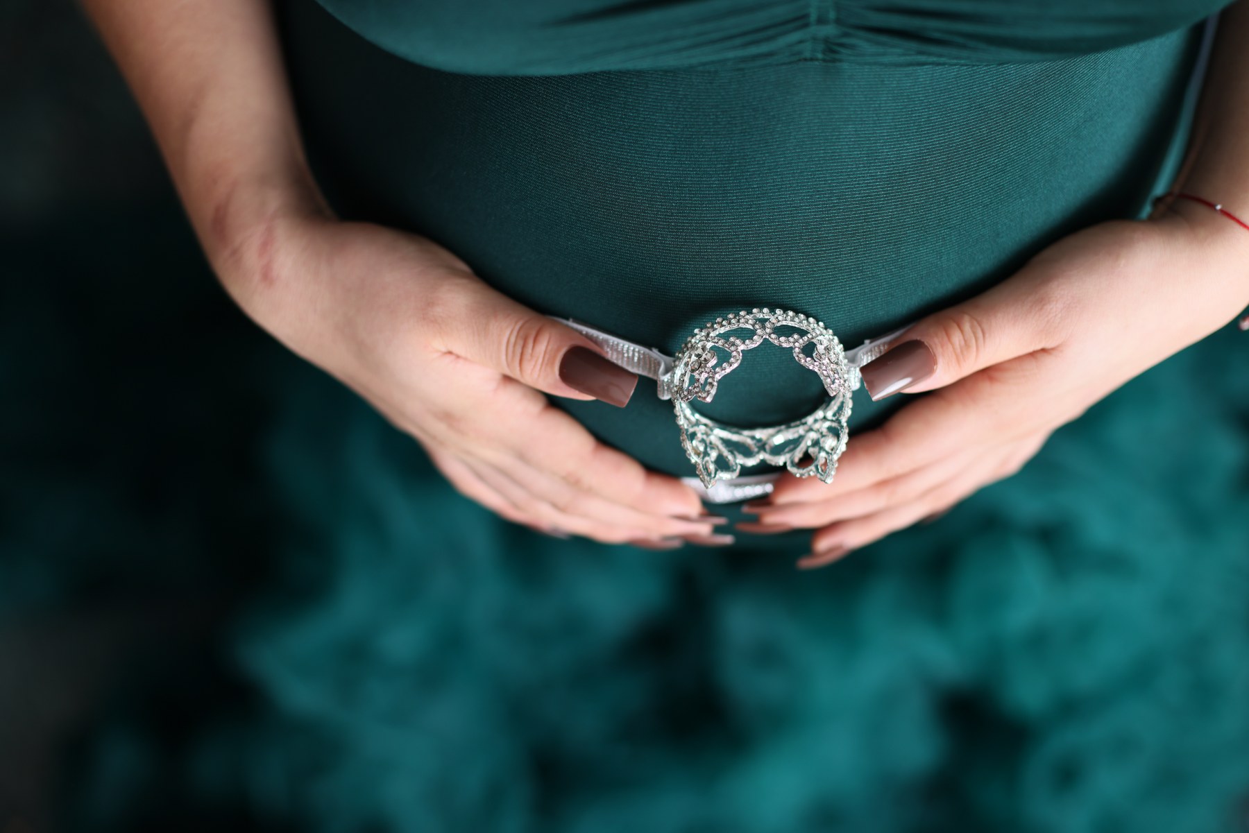 Close detail of hands resting on a teal maternity gown