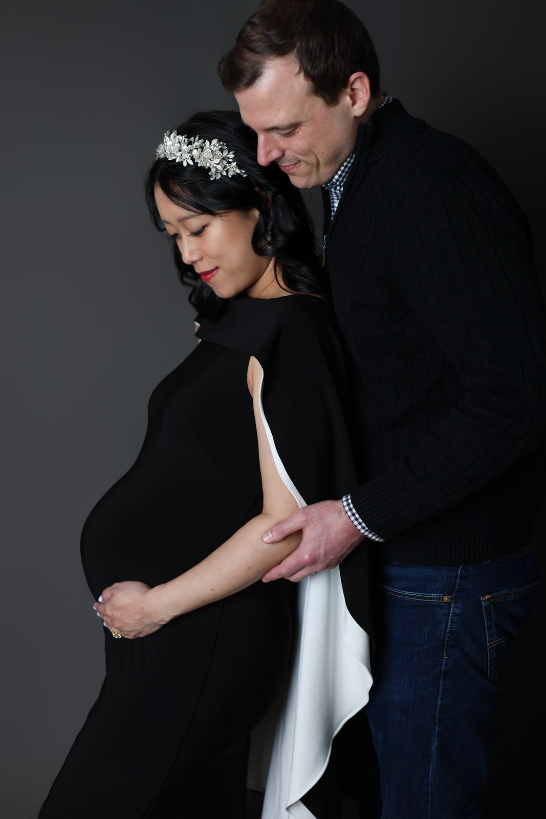 Expectant parents embracing with hands resting on the baby bump