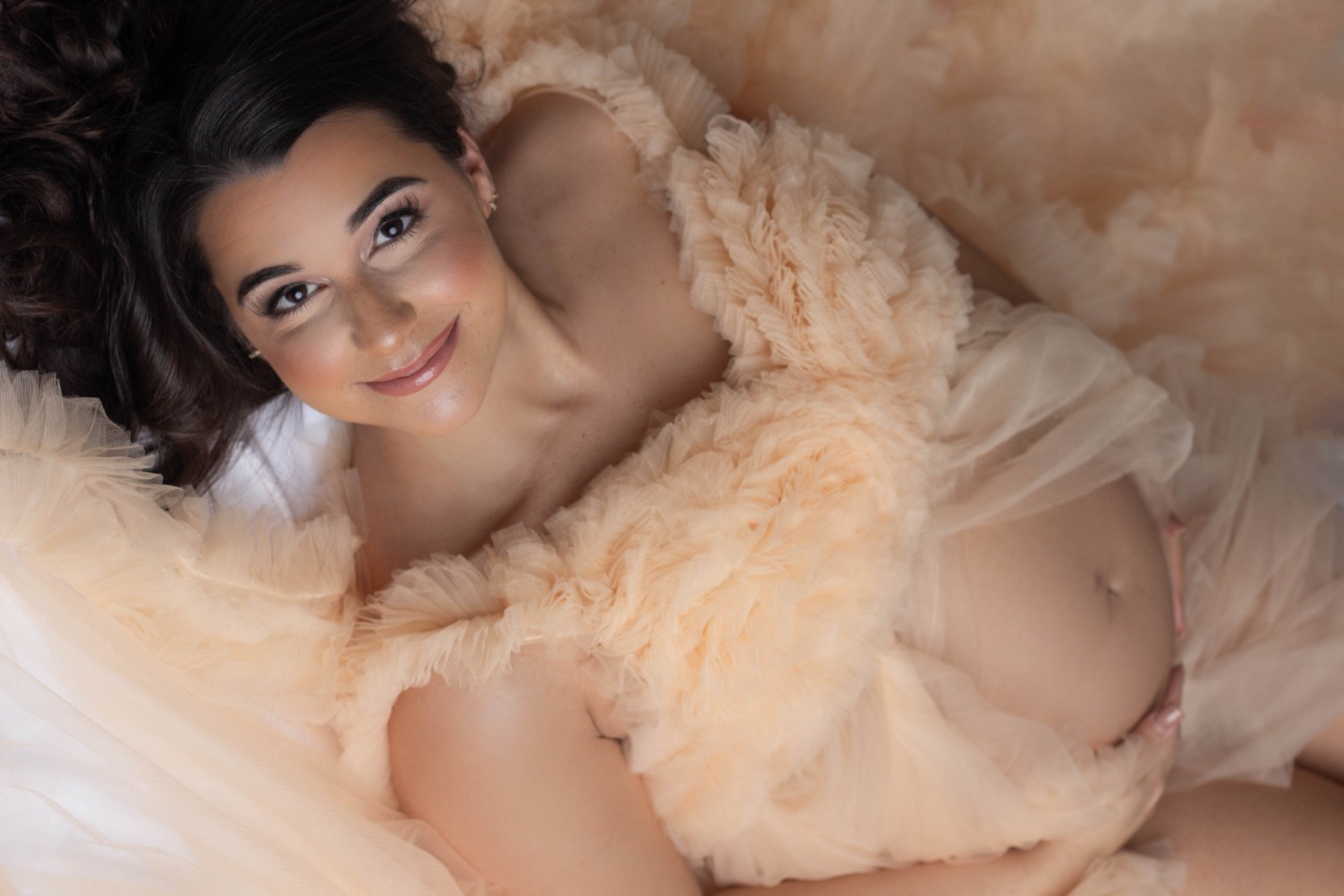 Close maternity portrait reclining in champagne tulle